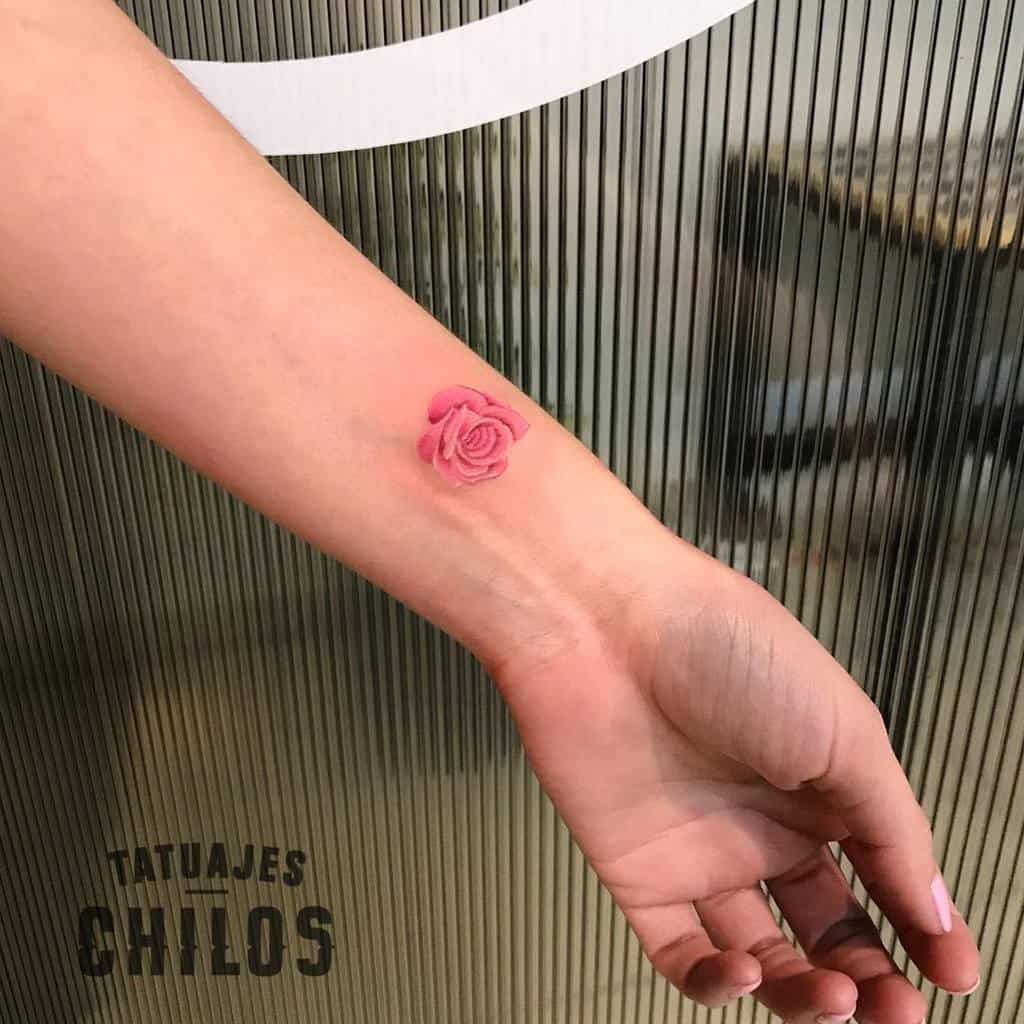 A small pink rose tattoo on a wrist