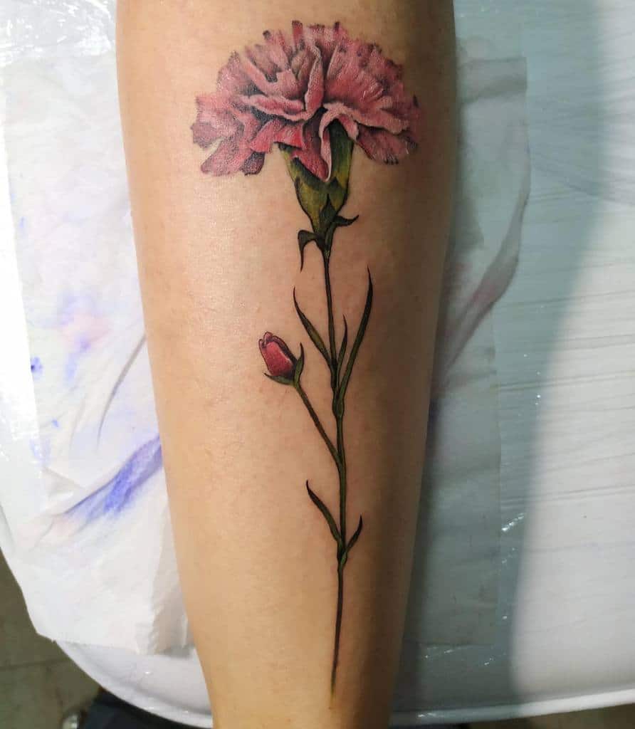 Tattoo of a pink carnation with a bud, showing detailed green leaves and stem