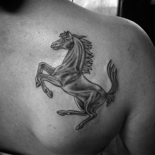 Shaded Ferrari horse tattoo on man's upper back, representing elegance, power, and passion for racing.