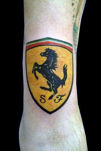 Vibrant Ferrari emblem tattoo featuring a black prancing horse on a yellow shield, inked on man's forearm.