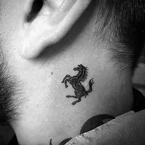 Minimalist Ferrari horse tattoo behind man's ear, symbolizing subtle luxury and refined style.