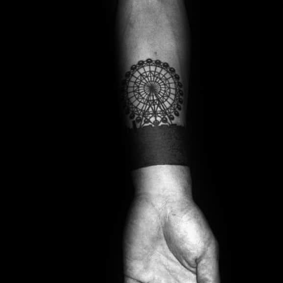 Bold Ferris wheel tattoo on the forearm, featuring intricate details above a solid black armband, creating a striking contrast and modern look.