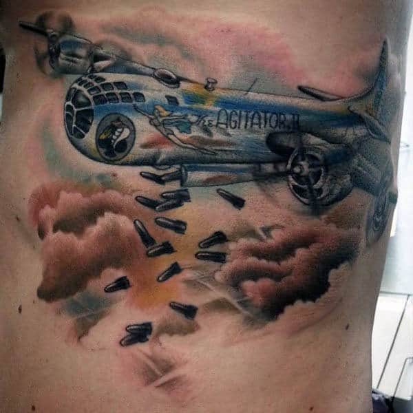 Tattoo of a WWII bomber airplane releasing bombs over a cloudy sky scene