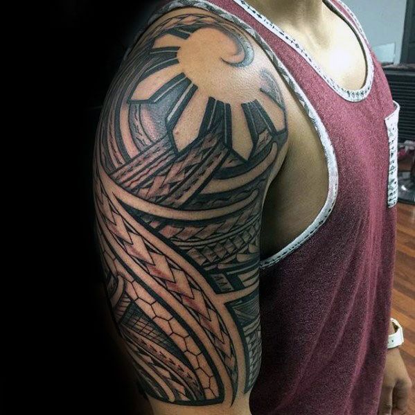 Filipino sun tattoo on the upper arm with tribal weaving patterns, bold rays, and dynamic curves forming a striking half-sleeve design.