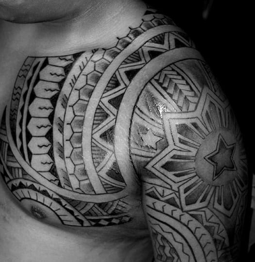 Filipino sun tattoo extending from chest to shoulder, featuring layered tribal bands, bold star details, and geometric symmetry in black ink.