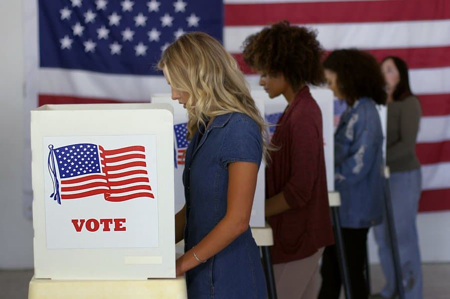 filling in ballots and casting votes in booths at polling station