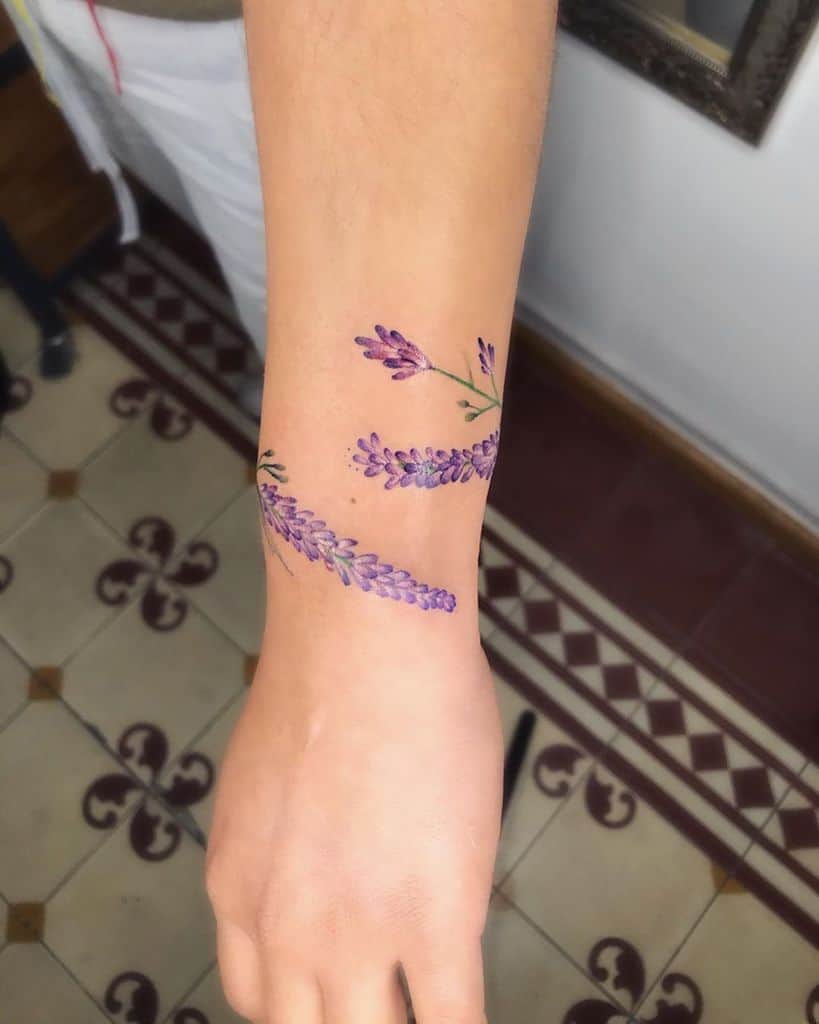 A beautiful lavender tattoo wrapping around the arm with purple lavender flowers and green stems, creating a flowing design.
