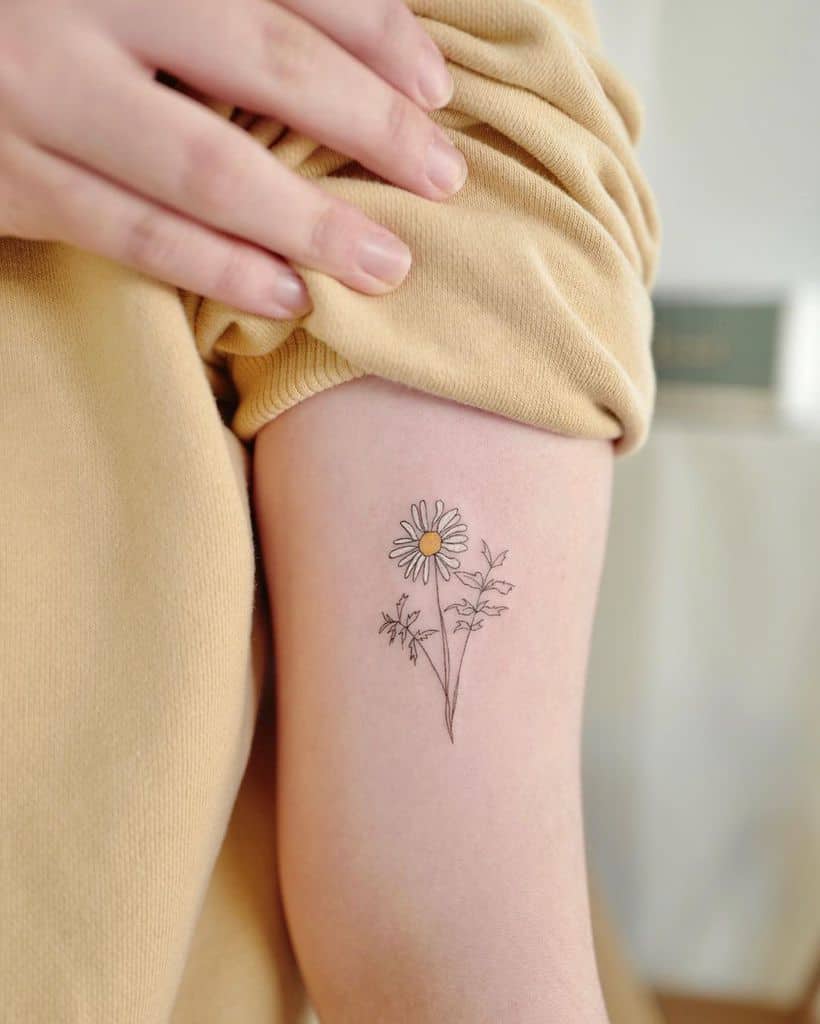 Bicep tattoo fine line color delicate daisy