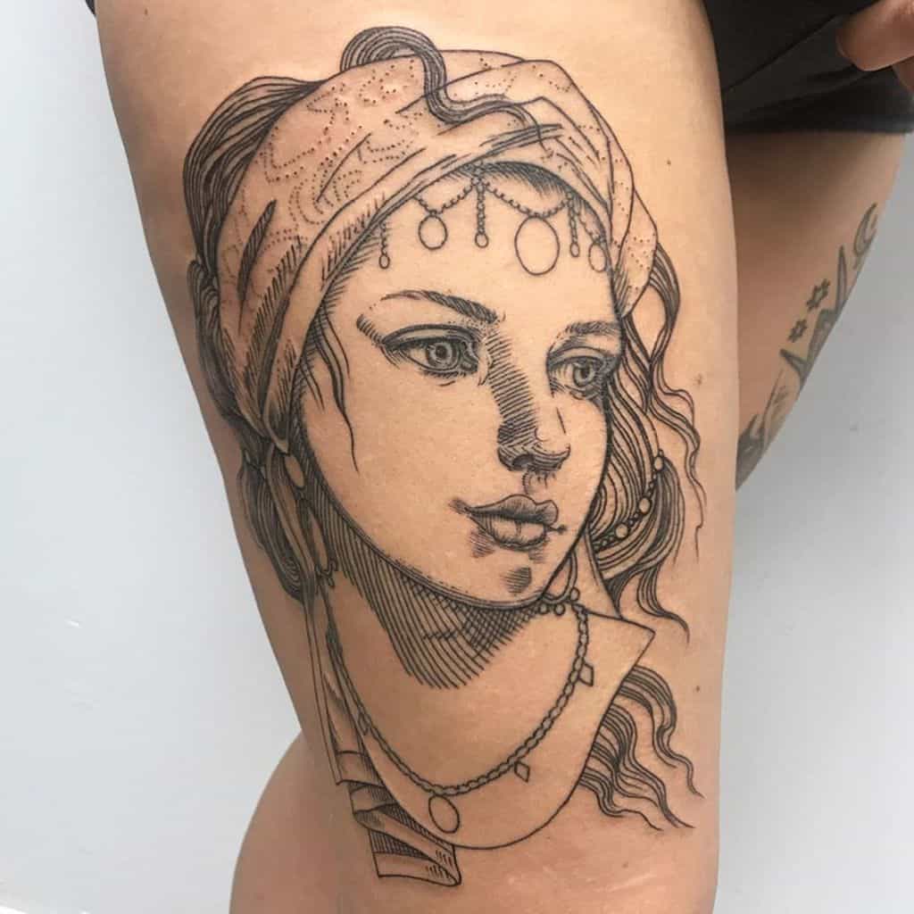 Black and grey tattoo of a gypsy woman with a headscarf, dangling jewelry, and delicate shading on the thigh in a vintage style.