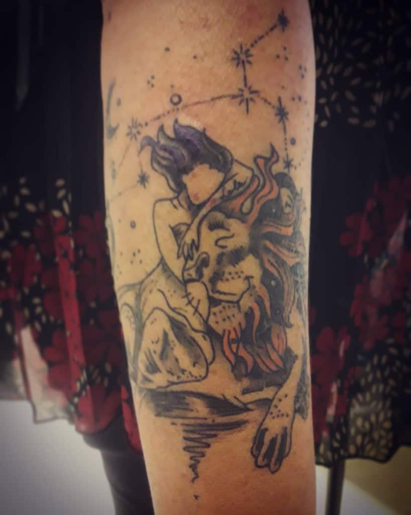 Dreamy Leo tattoo with a celestial woman resting on a lion, surrounded by the Leo constellation and mystical stars.