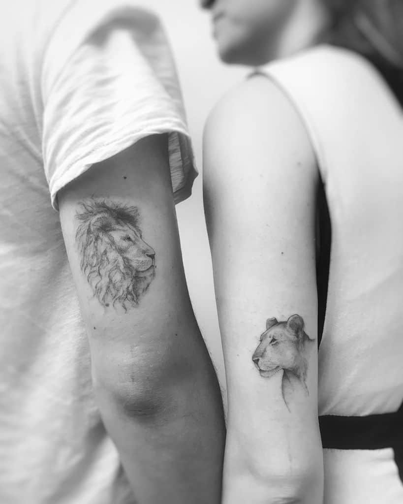 Matching lion and lioness tattoos on a couple’s arms, featuring soft shading and realistic details symbolizing strength and unity.