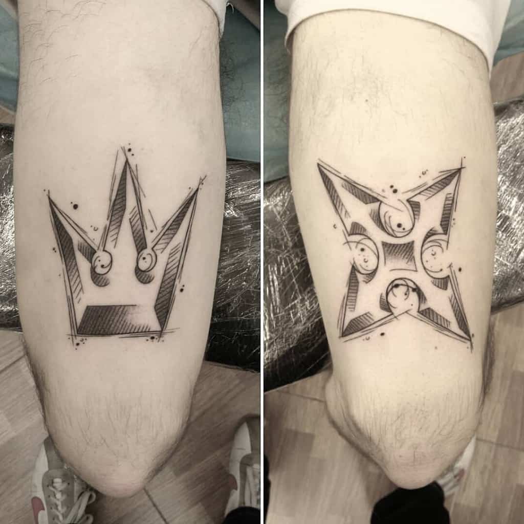 Kingdom Hearts-inspired black ink tattoos featuring the iconic crown on one arm and Roxas’s Oblivion shuriken symbol on the other, with fine line shading.