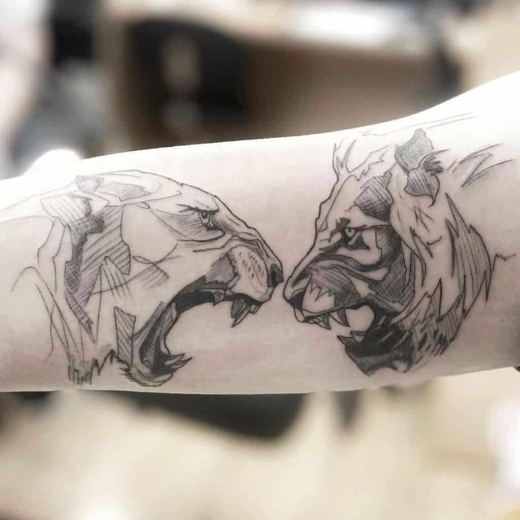 Dynamic forearm tattoo of a roaring lioness facing a fierce lion, created with sketch-style lines and shading for a bold, artistic effect.