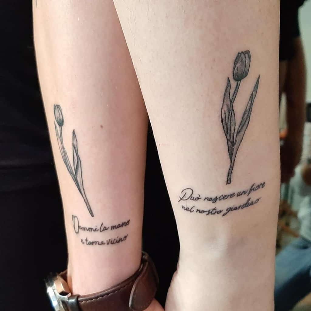 Matching tulip tattoos on forearms, each with a delicate flower and handwritten script in Italian, adding a meaningful touch to the design.