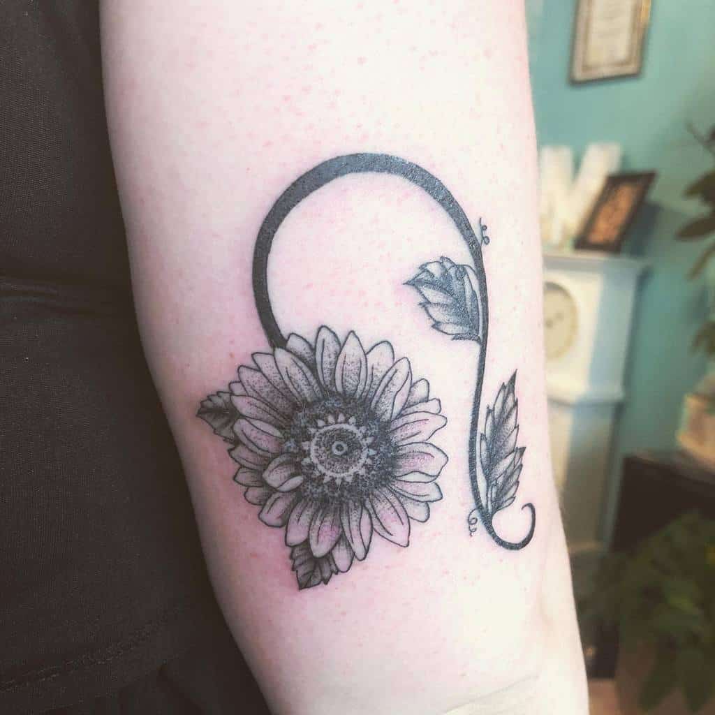 Tattoo of a sunflower with a curved stem and leaves on an arm
