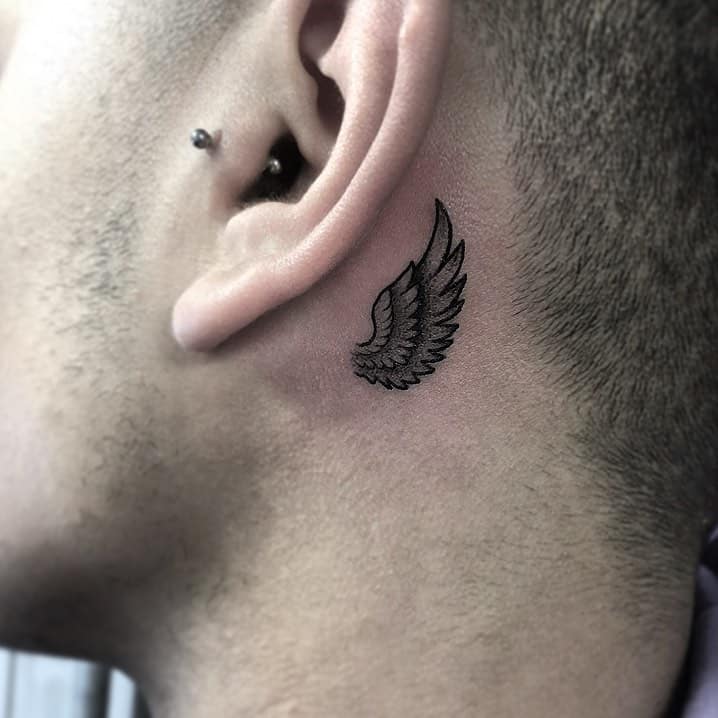 Small angel wing tattoo, with intricate feather details and bold black lines, creating a subtle yet impactful design