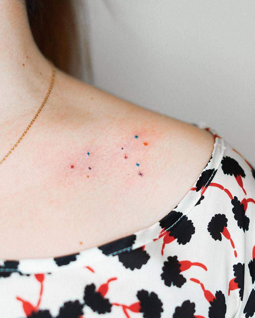 Fine-line constellation tattoo with colorful stars, subtly placed on the collarbone for a dreamy, celestial aesthetic.