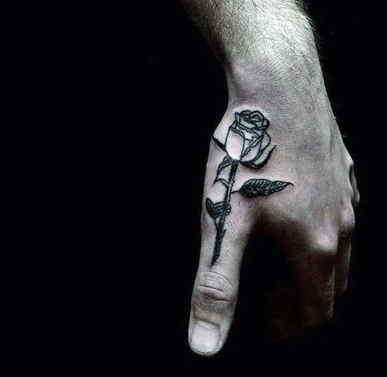 Hand with a black rose tattoo on the side of the thumb