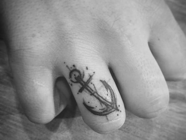 Black anchor tattoo on a finger