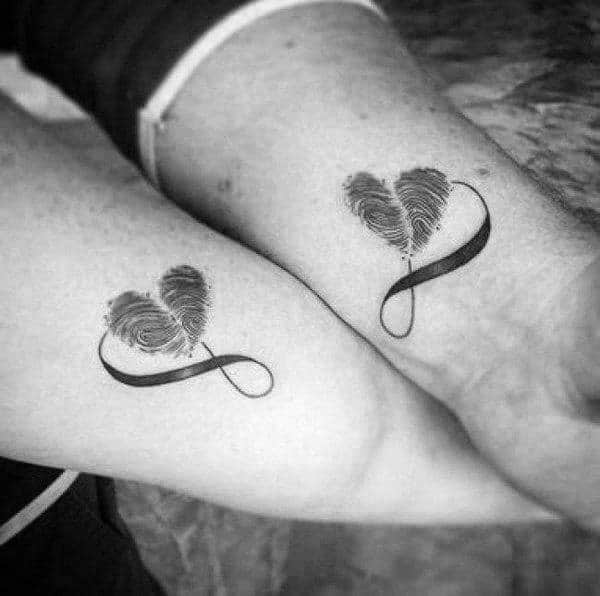 Matching forearm tattoos featuring heart-shaped fingerprints with an infinity symbol, representing eternal love and a unique bond.