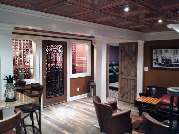 Basement with decorative tin ceiling, wine cellar, rustic barn door, and leather seating.