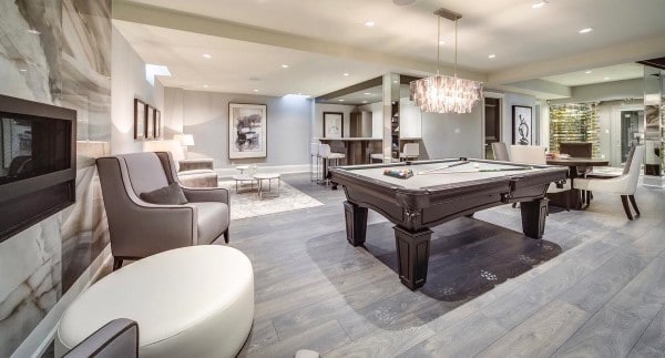 Luxury basement with pool table, elegant seating, crystal chandelier, and modern decor.