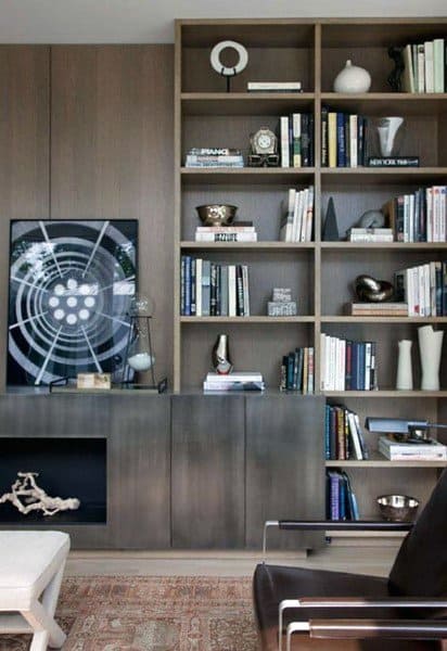Modern living room with dark wood shelves, books, art pieces, and a silver sculpture