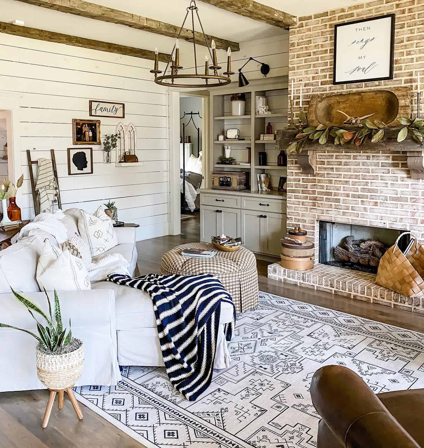 white shiplap walls chandelier brick fireplace sofa gray cabinet 