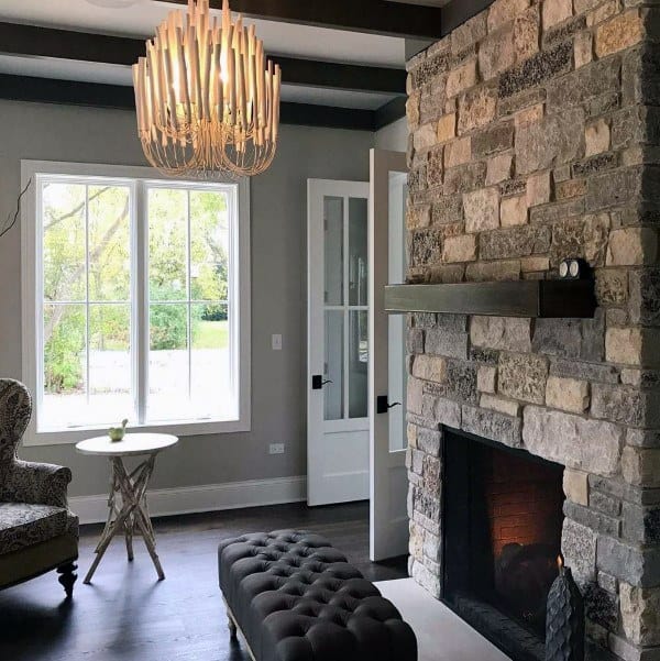 Rustic stone fireplace with a sleek dark wood mantel in a modern living room with elegant decor.