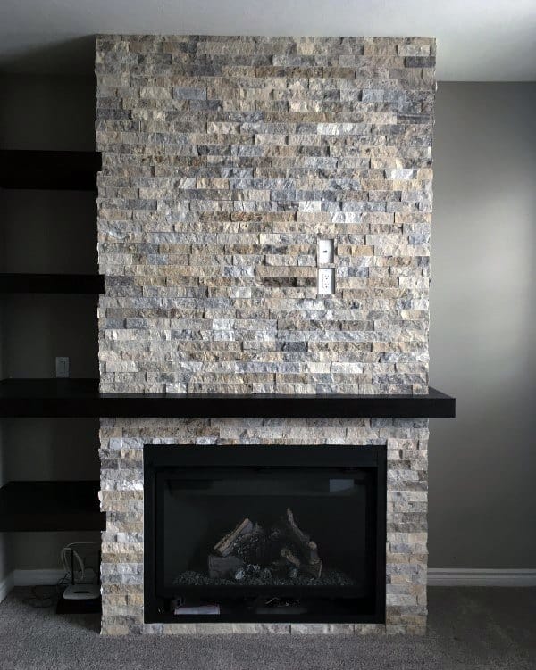 Contemporary stacked stone fireplace with black mantel and built-in shelving.