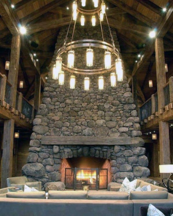 Grand living room with large stone fireplace, vaulted ceiling, and elegant tiered chandelier.