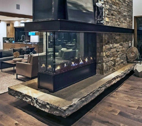 Glass-enclosed modern gas fireplace with a rustic stone base and stacked stone surround.