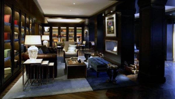 Elegant living room with dark wood panels, resembling a library, and cozy seating around a coffee table