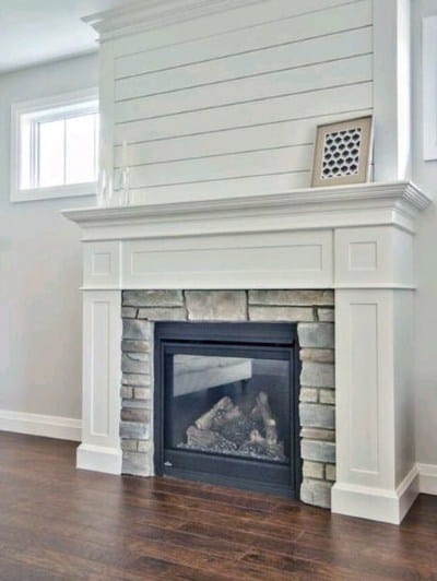 White shiplap fireplace with a stone surround, classic wood mantel, and black gas firebox.
