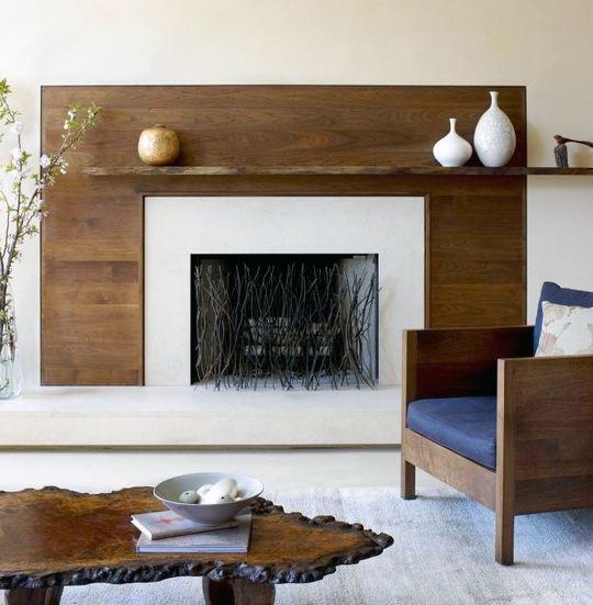 Modern fireplace with a wood-paneled surround, minimalist mantel decor, and a natural wood table.