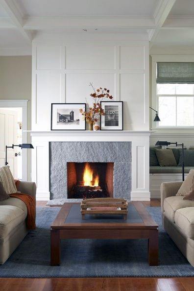 White paneled fireplace with a stone surround, decorated mantel, and traditional furniture layout.