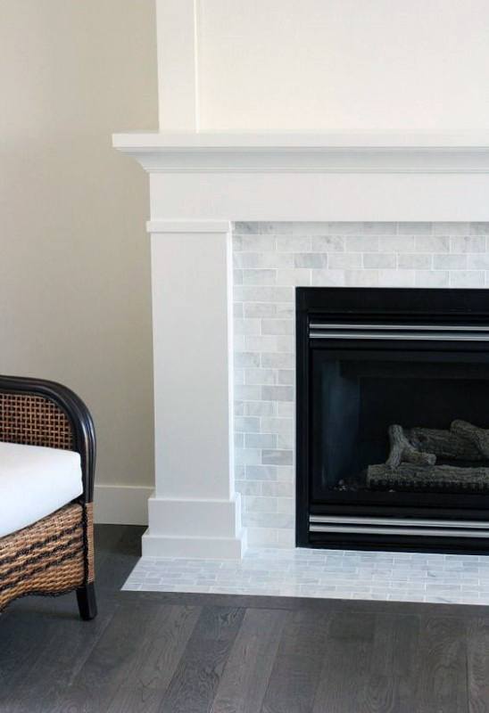 This fireplace features a sleek white mantel with subway tile surround and a black framed insert.
