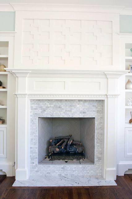 Elegant white fireplace with marble tile surround and decorative geometric panel above.
