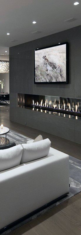 Modern living room with sleek linear fireplace, mounted TV, and elegant white sofa.
