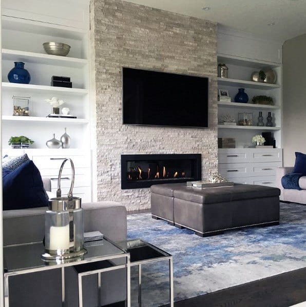 Gas fireplace with a black frame set in a white stacked stone wall.