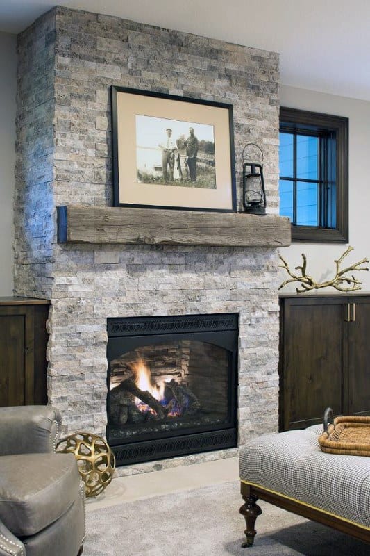 Stone fireplace with a rustic wooden mantel, framed photo, lantern decor, and cozy living room accents.