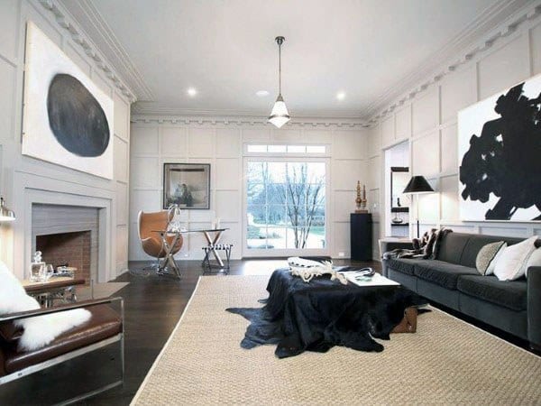 Elegant living room with fireplace, modern art, dark sofa, and home office in the corner.