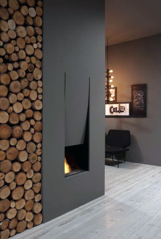 Modern fireplace with sleek black surround and stacked firewood wall for rustic contrast.
