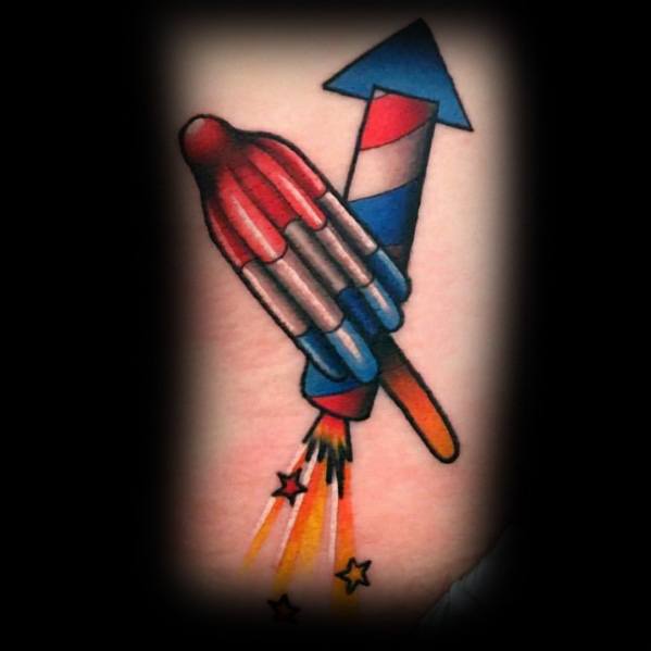 Tattoo of a rocket firework and a red, white, and blue popsicle combined, designed with bold colors and a playful patriotic theme.