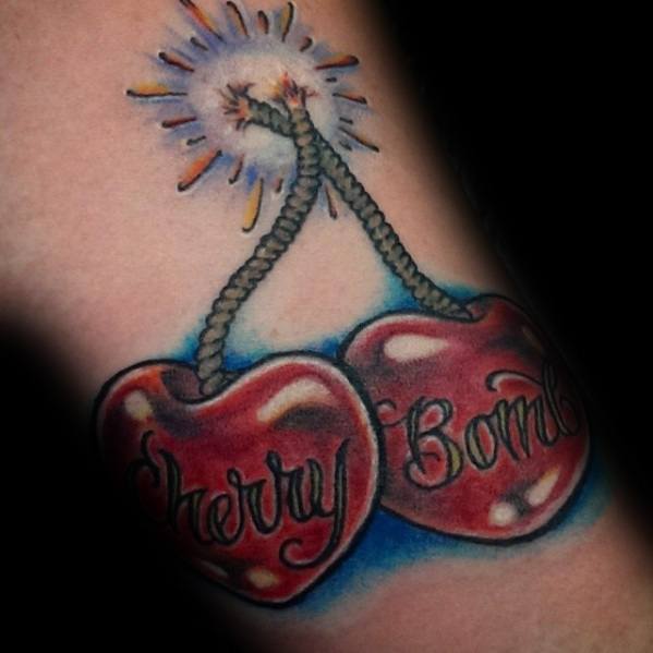 Tattoo of two cherries with lit fuses, labeled "Cherry Bomb," designed with bold red shading and dynamic sparks for a vibrant and edgy look.