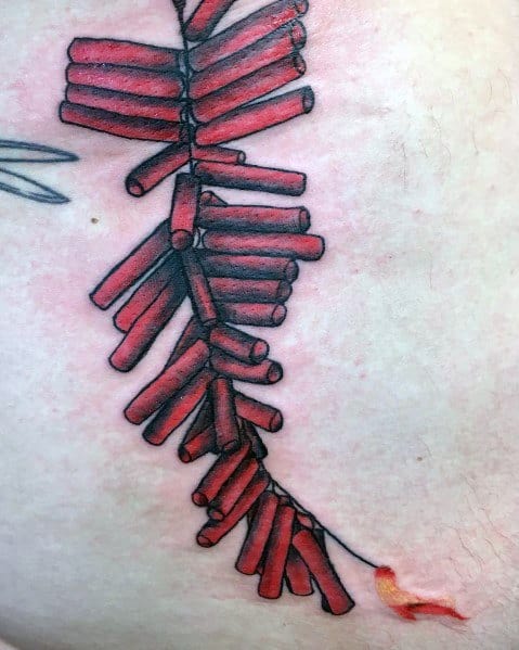 Tattoo of a long string of red firecrackers with a lit fuse at the bottom, designed with bold shading and realistic details for a dynamic look.