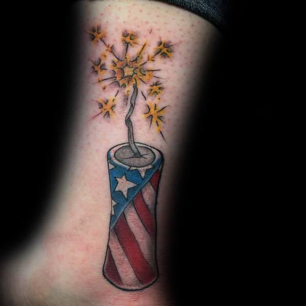 Tattoo of a firecracker wrapped in an American flag design with a lit fuse sparking, symbolizing patriotism and celebration in a bold style.