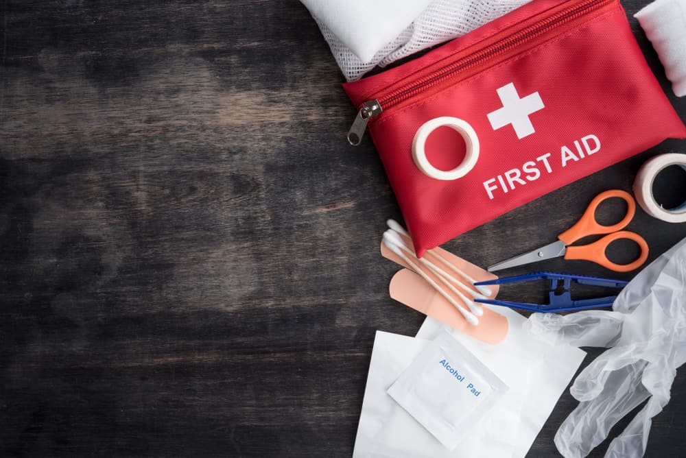 first aid medical kit on wood background, top view