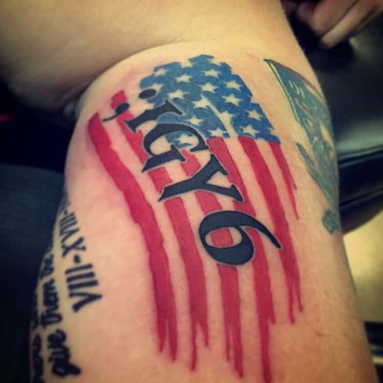 Tattoo of a stylized American flag with "; IGY6" text in black ink on an arm