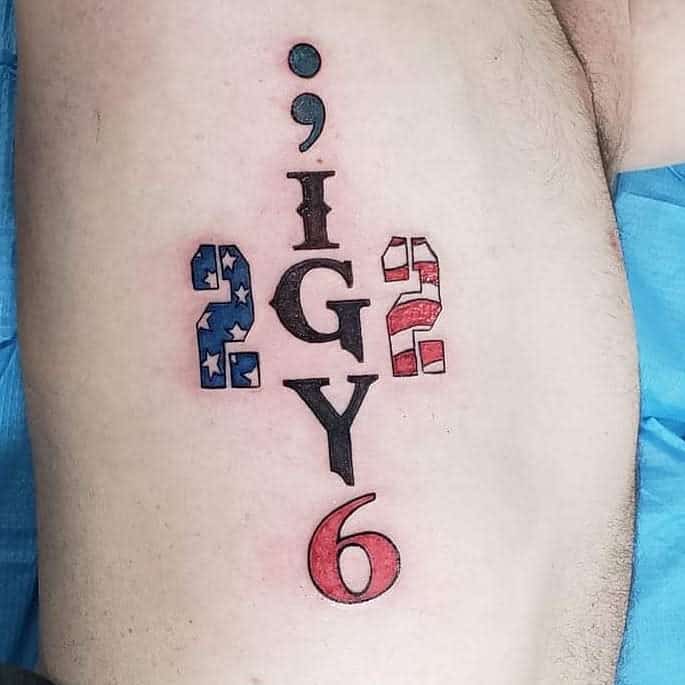 A tattoo featuring a semicolon positioned above "IGY6" with "22" incorporated into an American flag design on each side